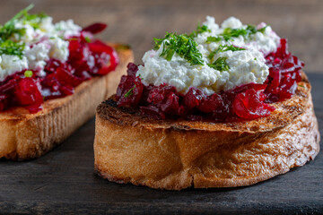 Toast from a slice of bread with white cream cheese, stewed beetroot pulp, seeds and green dill. Delicious breakfast on morning