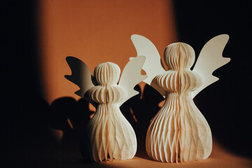 DIY paper angels. Hand made white angel on orange brown background. New Year toys. Christmas greeting card. Craft decor. Faith and religion concept.