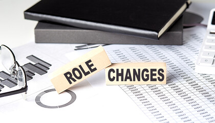 ROLE CHANGES - text on a wooden block with chart and notebook