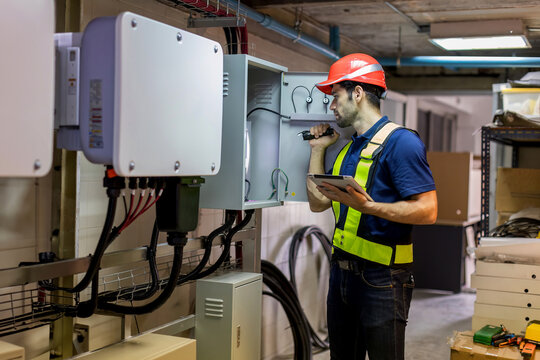 Electrical Engineer Working In Control Room. Electrical Engineer Man Checking Power Distribution Cabinet In The Control Room