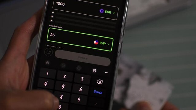 Overseas Filipino Worker or OFW sending money to the Philippines from Europe with the use of a wire transfer app on a smartphone