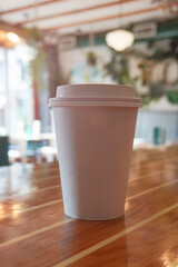 Detail of coffee paper cup. White paper cup in an unfocused coffee shop background.