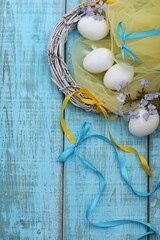 Eggs on the table, Easter, holiday, greetings, day, blue and yellow ribbons, blue wooden background, top view, free space, place for text