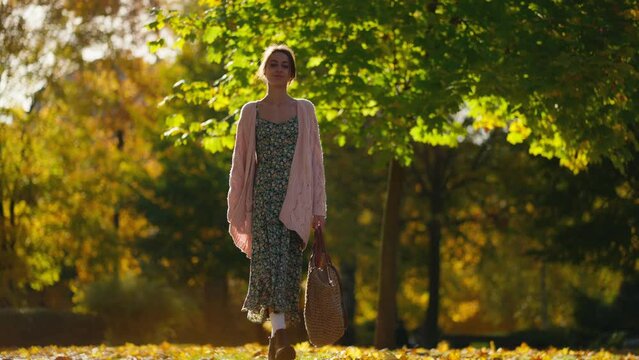 woman wearing long knitted sweater or cardigan walks in natural maple park with golden foliage. Woman in nature at warm fall day. Active lifestyle. Female outdoors. girl walk in autumn park