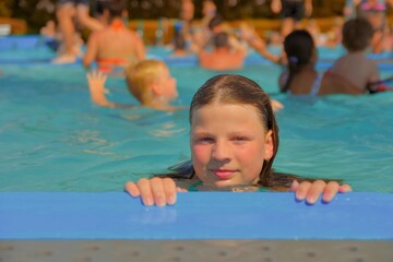 A little girl at the edge of the pool. Little girl in the pool. Young woman on the edge of the...