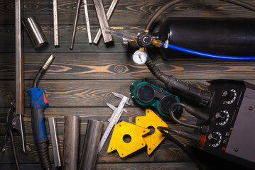 Welding concept background top view. Semi automatic welding machine and metal parts on the floor...