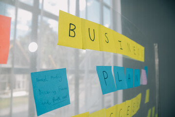 Young creative team professional using post it notes in glass wall to writing strategy business plan to development grow to success.