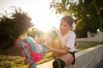 Roller skating. Girl puts on roller skates while sitting on a park bench