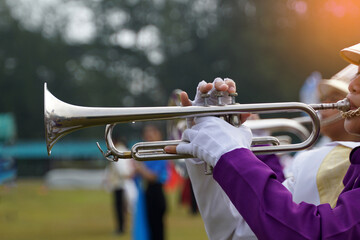 -	Close-up of student's hand pressing the button of a trumpet to chase a musical note, playing a song while practicing for a school parade. Soft and selective focus. 