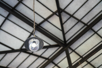 A ceiling lighting lamp which is installed at the factory warehouse. Interior electrical equipment object.