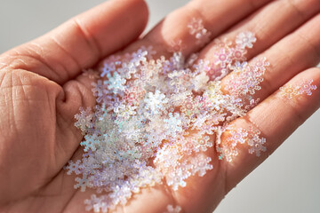 Sequins in the shape of snowflakes on the hand.