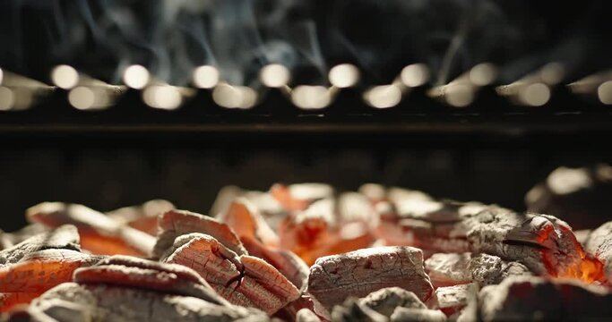 Flames burst from red-hot coals and break through grill grate. Mesmerizing spectacle of dancing flames, beckoning with its light and warmth. Best time to gather whole family around grill. Cinematic AD