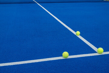 three balls on the lines of a blue paddle tennis court, racket sports concept