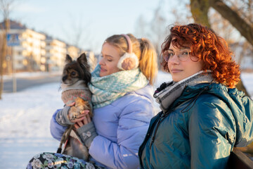 Two women wait for a bus in winter.