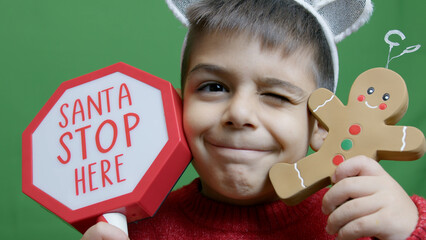 Cute boy with christmas sweater and deer alntlers holding sign Santa stop here and gingerbread man....