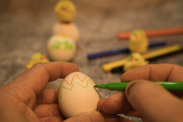 An egg is being painted for Easter. More crayons can be seen in the background.