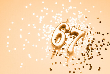 67 years celebration festive background made with golden candles in the form of number Sixty-seven lying on sparkles. Universal holiday banner with copy space.