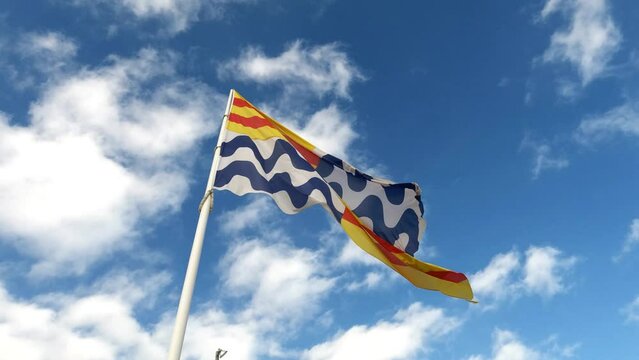 Flag of the city of Badalona, Spain flying over the blue sky.