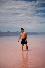 Man walking in shallow Pink Salt Lake in Utah near Salt Lake City.  Located in the Southwest of the...