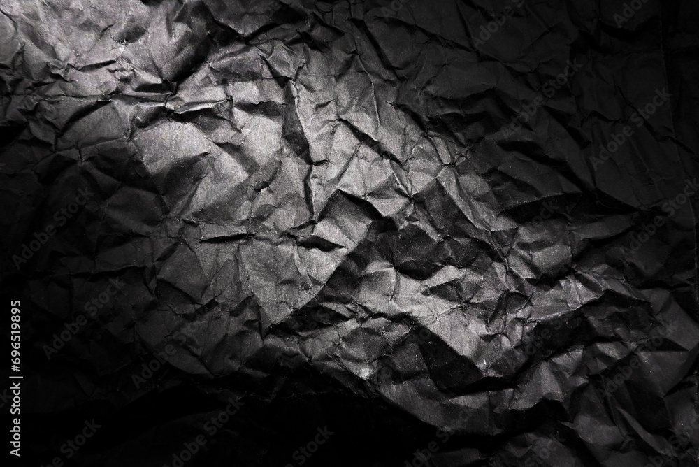 Poster texture of crumpled black paper with gradient. dark paper background with wrinkles and folds