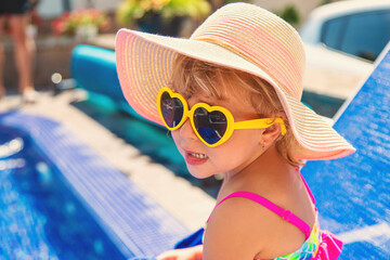 Child near the pool in sunglasses. Selective focus.