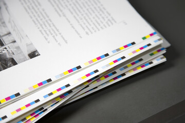 White sheets with with the text and paint around the edges are stacked in a printing house. An abstract background of sheets of paper.
