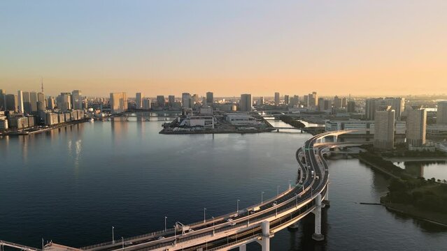 tokyo city rainbow bridge aerial view drone,traffic on highway street crossing the sea bay kotoku district in the background from odaiba ward at sunrise dawn