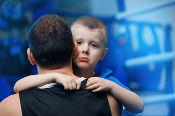 Boy boxer son hugs his father after loss fight. Concept supporting and help children with...
