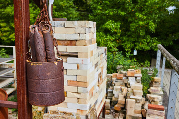 Rusty Bucket and Bricks at Construction Site with Greenery Background