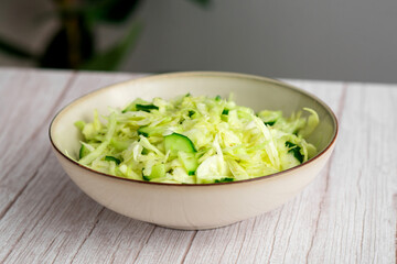 Healthy coleslaw salad with cabbage and cucumber served on a wooden surface