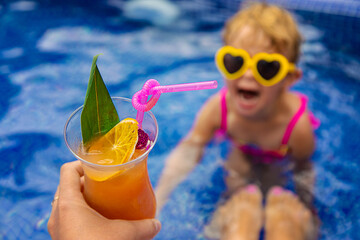 A woman in the pool drinks a cocktail. Selective focus.