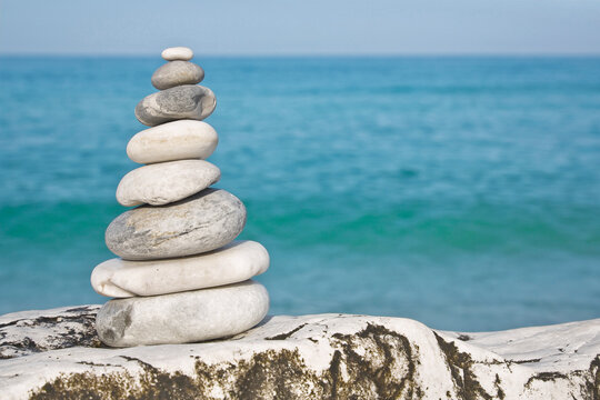 White and gray stones softly rounded against a blue sky and calm sea - tranquil scene and meditating concept