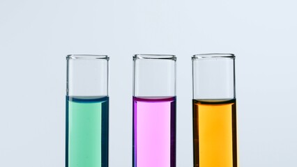 Concept of science and biotechnology. Laboratory glassware on white background. Test tubes filled with pink, green and yellow liquid. Close up.