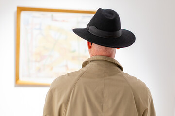 man with big hat looking at a painting in a gallery