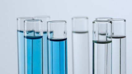 Science and biotechnology creative concept. Close up shot of laboratory glassware on white background. Test tubes with transparent and blue liquid fluid in laboratory, scientific expertise.