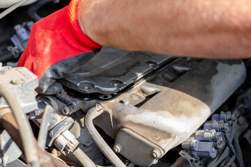 Car repairs. The auto mechanic removes the gas distribution mechanism cover