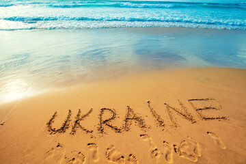The inscription of Ukraine on the sandy beach. Gradient color. Color of the flag of Ukraine
