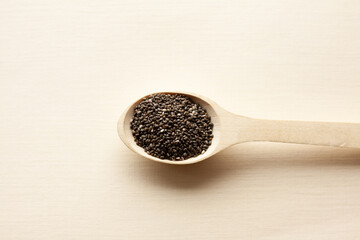 chia grains in a wooden spoon on a light background
