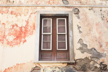 Fototapeta na wymiar Ancient architecture. Abandoned window. Broken home facade. Wooden door. Damaged building. Peeling paint wall. Disaster exterior.