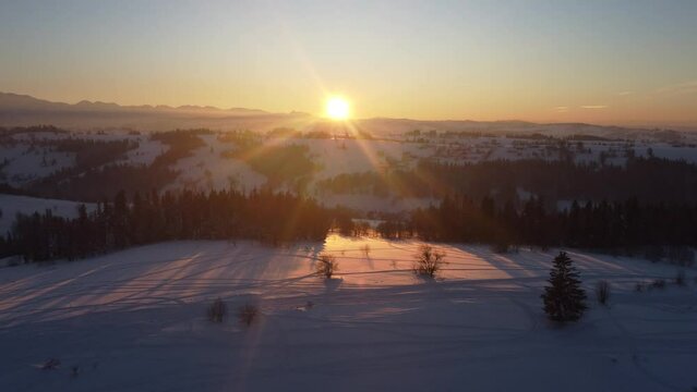 Przelot nad szczytem góry na Podhalu zimą z zachodem słońca w tle - 4K