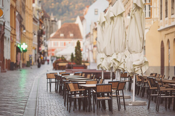 Umbrellas and tables of the bar in the street, Brasov, Romania. Coffeehouse cafe restaurant Outdoor...