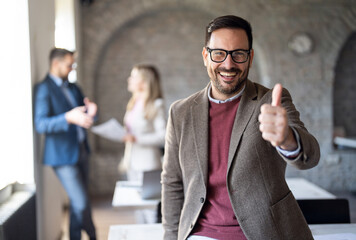 Portrait of happy businessman showing thumbs up with hand