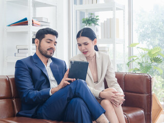 Portrait business teamwork woman and man asian two people meeting sitting on sofa talk idea hand holding laptop notebook on table ready for happy working new project job online sale inside home office