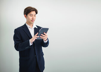 Business man portrait asian one person wearing a black suit handsome standing looking success committed hand holding mobile phone and laptop ready for work inside the office, with white background