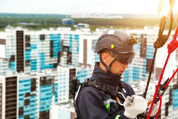 Industrial mountaineering worker in uniform on residential facade building