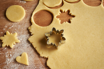Cutting out star shapes from raw pastry dough to prepare homemade Linzer Christmas cookies