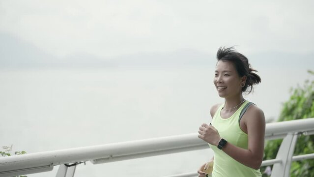 young asian woman exercising by running outdoors in park by the sea