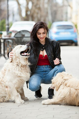 girl walking in the city with his dogs. Woman playing with a white dog. Dog hugging