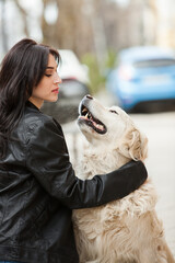 girl walking in the city with his dogs. Woman playing with a white dog. Dog hugging