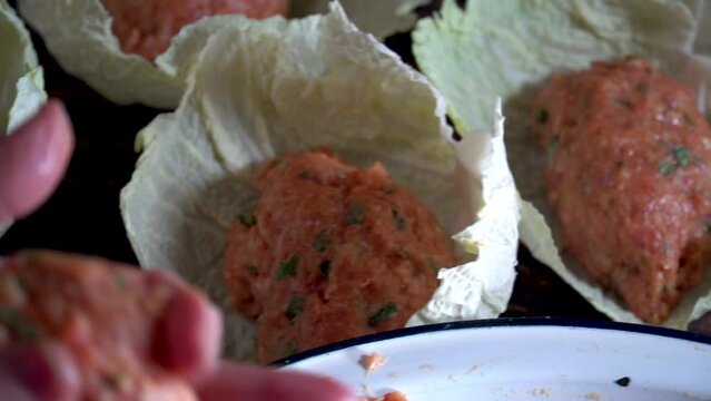 A person wraps balls of minced meat on cabbage leaves, spanish food, "puchero" balls.